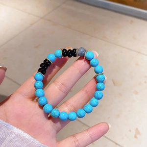 Close-up of handmade turquoise and black onyx beaded bracelet with gold spacers on hand