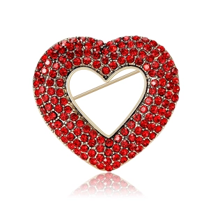Elegant vintage gold heart brooch with red rhinestones and hollow center on white background