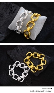 Detailed view of gold and silver chunky chain bracelets on grey and black backgrounds
