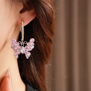 Close-up of pink and clear butterfly drop earrings with cubic zirconia on model