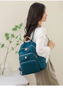 Dettaglio zaino in nylon blu navy con cerniere multistrato e decorazioni di perle