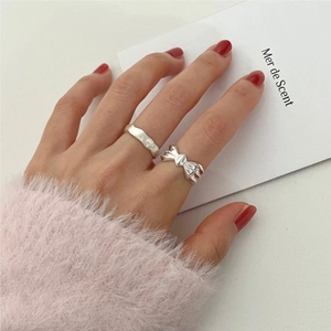 Detail showing a 925 sterling silver bow ring and textured band set worn by a model