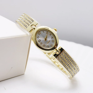 Macro shot of gold oval quartz watch with rhinestones on dial and metal band