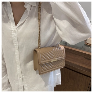 Detail of khaki leather crossbody bag with V-shaped quilting and gold chain strap