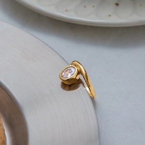 Close-up of 18K gold plated ring with oval zircon on a metallic tray edge