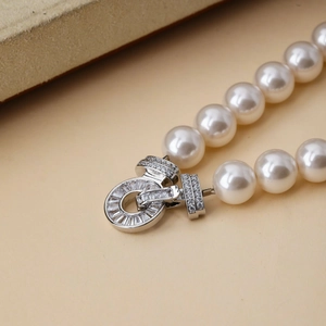 Close-up of white pearls with a luxury diamond-encrusted circular buckle clasp