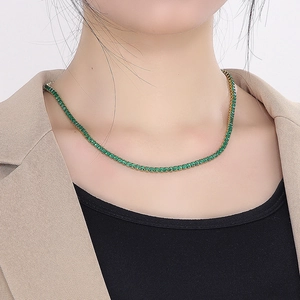 Detailed view of luxury 18K gold plated tennis necklace with green square gemstones on neck