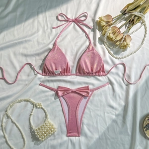 Macro detail of sparkly pink bikini set with side tie bows and shimmery fabric texture