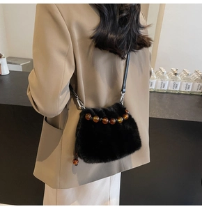 Close-up of black faux fur bucket bag with brown beads on model wearing khaki blazer