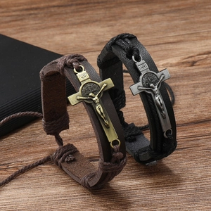 Detail of vintage leather braided bracelets with metal cross pendants on wooden surface