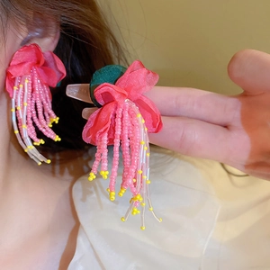 Detail shot of floral tassel earrings with pink and yellow beads on model
