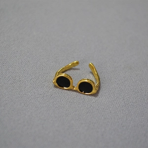 Unique sunglasses shaped gold brass ring with black lenses on grey fabric