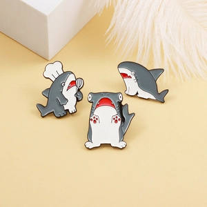 Three creative shark enamel pins featuring chef shark and hammerhead shark on yellow base