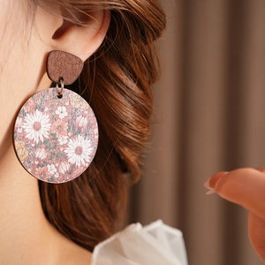Close-up of vintage wooden round earrings with floral painting on a model's ear
