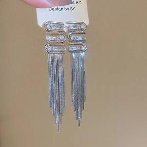 Detailed close-up of sparkling silver tassel earrings with geometric diamond accents