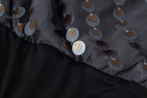 Detailed close-up of sequins stitched on mesh and knit fabric for women's V-neck bodysuit