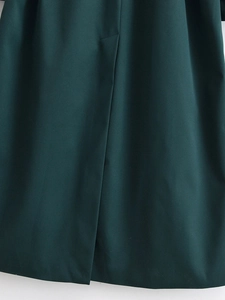 Detailed view of the dark green coat hem showing high-quality vent stitching and woven fabric