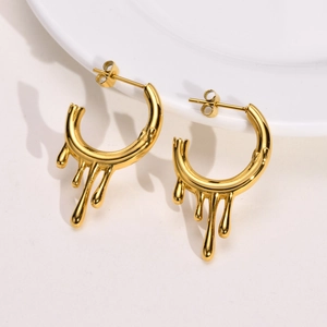 Macro shot of liquid metal drop C-shaped earrings in polished gold with mirror finish