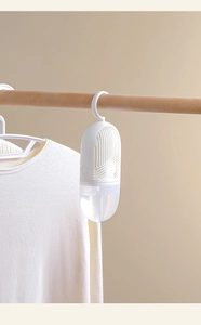 Detail view of a white hanging wardrobe dehumidifier on a wooden hanger with knitwear
