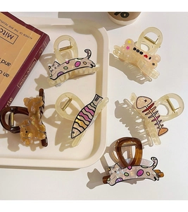 Detailed view of acetate dog hair claw clip and animal motifs on a white tray