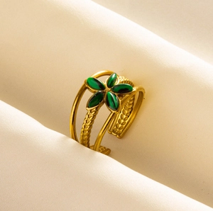Detail of vintage gold stackable ring featuring a green flower motif and woven texture