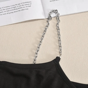 Detail eines schwarzen gerippten Tops mit silbernen Ketten-Trägern auf hellem Hintergrund