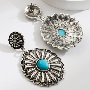 Detail of silver drop earrings with floral texture and turquoise gemstone inlay