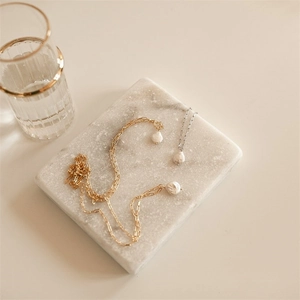 Elegant gold and silver paperclip link necklaces with baroque pearls on marble surface