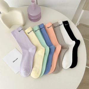 Eight pairs of colorful ribbed cotton socks with letter print on a minimalist table