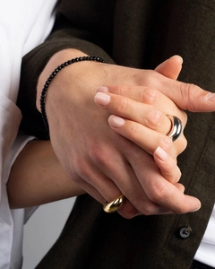Detail of minimalist gold and silver dome rings worn with a black faceted bead bracelet