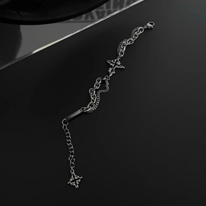 Detailed close-up of a silver-black double chain bracelet with a dark gothic cross charm