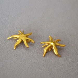 Close-up of gold-plated abstract flower earrings with textured metallic finish