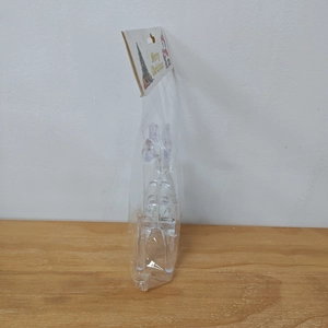 Detail of acrylic Christmas reindeer ornament in retail packaging on a wood surface