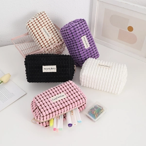 Detailed interior of corduroy makeup bag filled with highlighters and office supplies