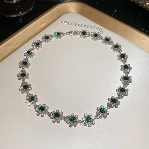 Detailed shot of silver flower pendant necklace with green gemstones and shiny crystals