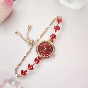 Montre bracelet dorée élégante avec cadran rouge et motif de feuille sur fond rose