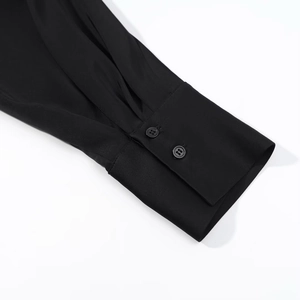 Dettaglio dei polsini a due bottoni su una camicia nera in pizzo dal tessuto liscio