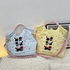Close-up of quilted cat embroidery on light blue and yellow padded tote bags