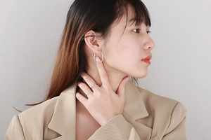 Macro detail of large silver hoop earrings and minimalist rings on a female model