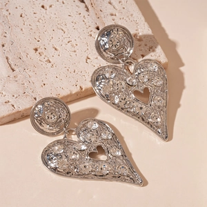 Detailed view of silver heart earrings with textured metal and sparkling rhinestones
