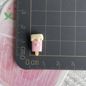 Luminous pink popsicle resin charm on scale mat showing 2cm size for jewelry making