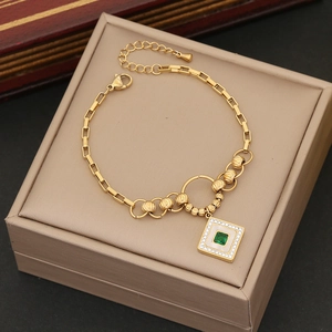 Golden chain and bead necklace with green gem square pendant on a beige jewelry box