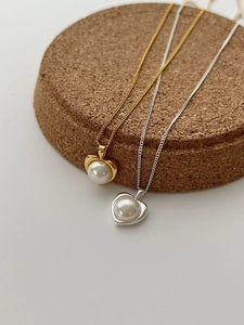 Dettaglio di collane con ciondolo a cuore e perla in finitura oro e argento