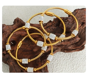 Detail of 18K gold-plated snake chain bracelets with pavé zircons on a rustic wood stand