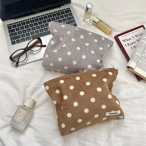 Close-up of corduroy polka dot toiletry bags in grey-purple and tan brown finishes