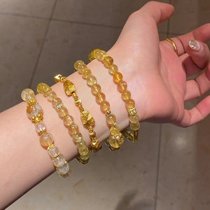 Macro detail of citrine flower zircon bracelets layered on a wrist in elegant gold tones