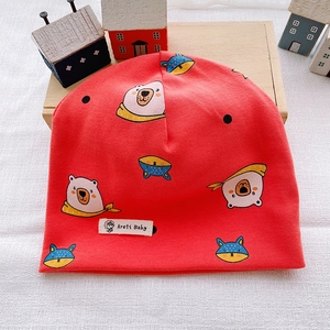 Detail of red cotton baby beanie with cute cartoon bear and fox prints and logo tag