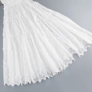 Detailed view of white floral lace embroidery and hollow-out patterns on the dress hem