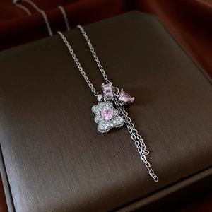 Detail of silver necklace with pink gemstone bear pendant on dark textured gift box