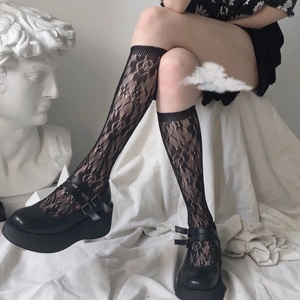 Close-up of black floral lace knee-high socks paired with platform Mary Jane leather shoes